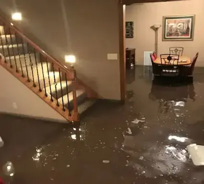 Standing water covering the first floor of a home near the stairs before extraction begins.