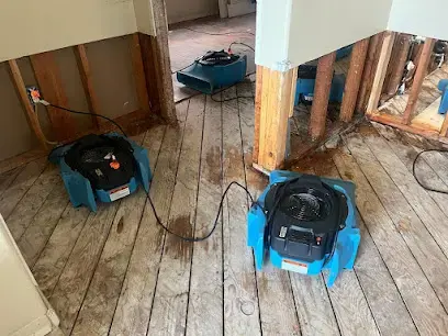 Air movers drying a wood subfloor where the lower walls were cut open, Granada Hills dry-out