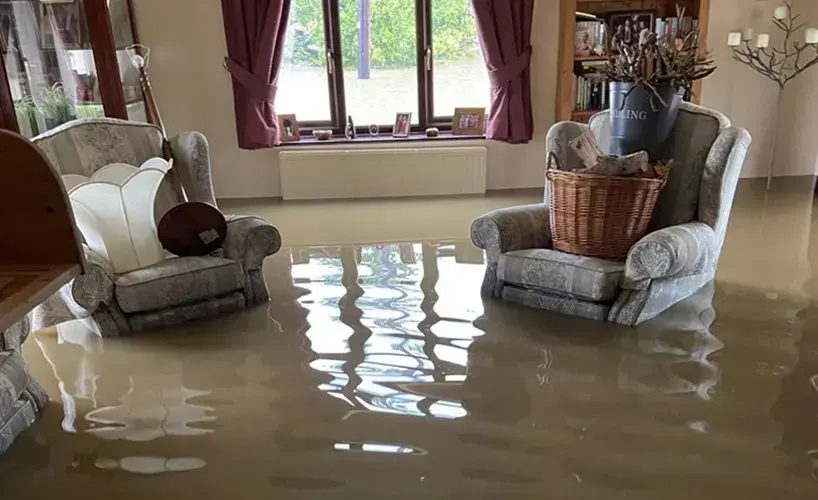Floodwater standing in a living room around armchairs, Granada Hills storm flood cleanup